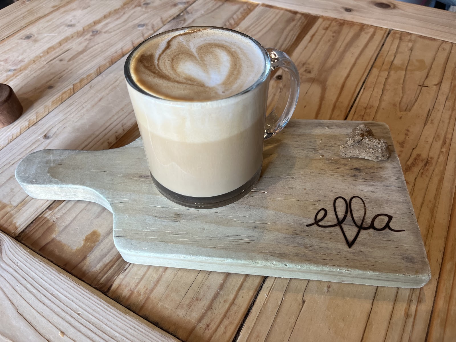 A golden butter croissant dusted with a cloud of icing sugar on a dark wooden board