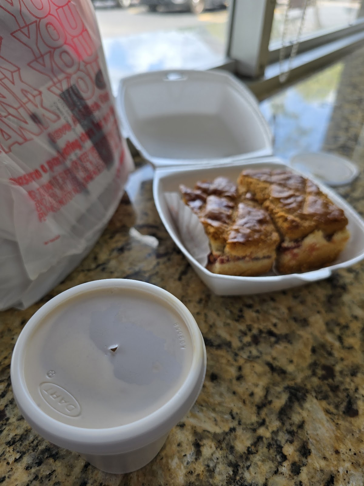 Two golden croissants on a dark plate beside a glass of milk