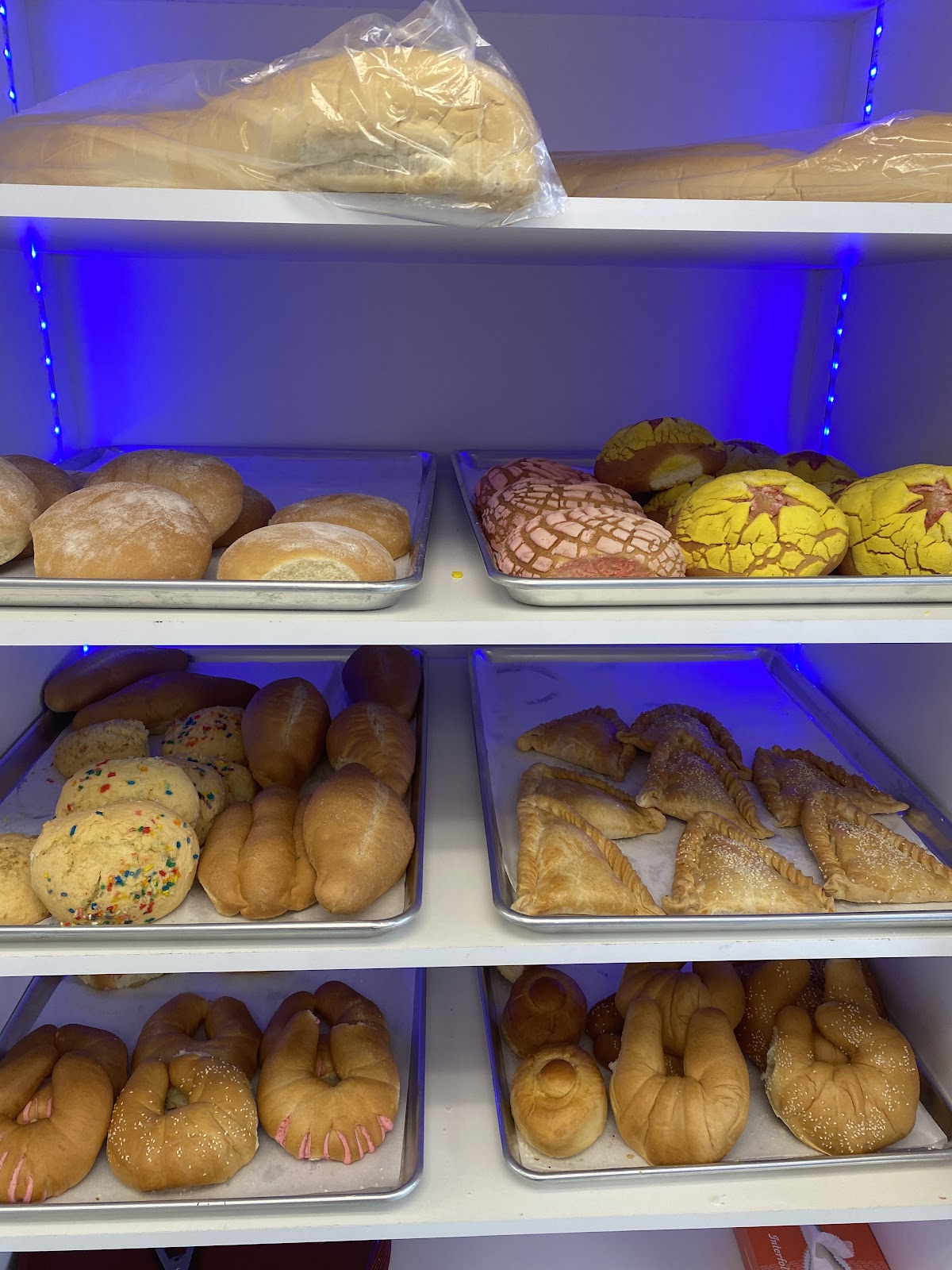 Warmly lit shelves stacked with rustic loaves and rolls
